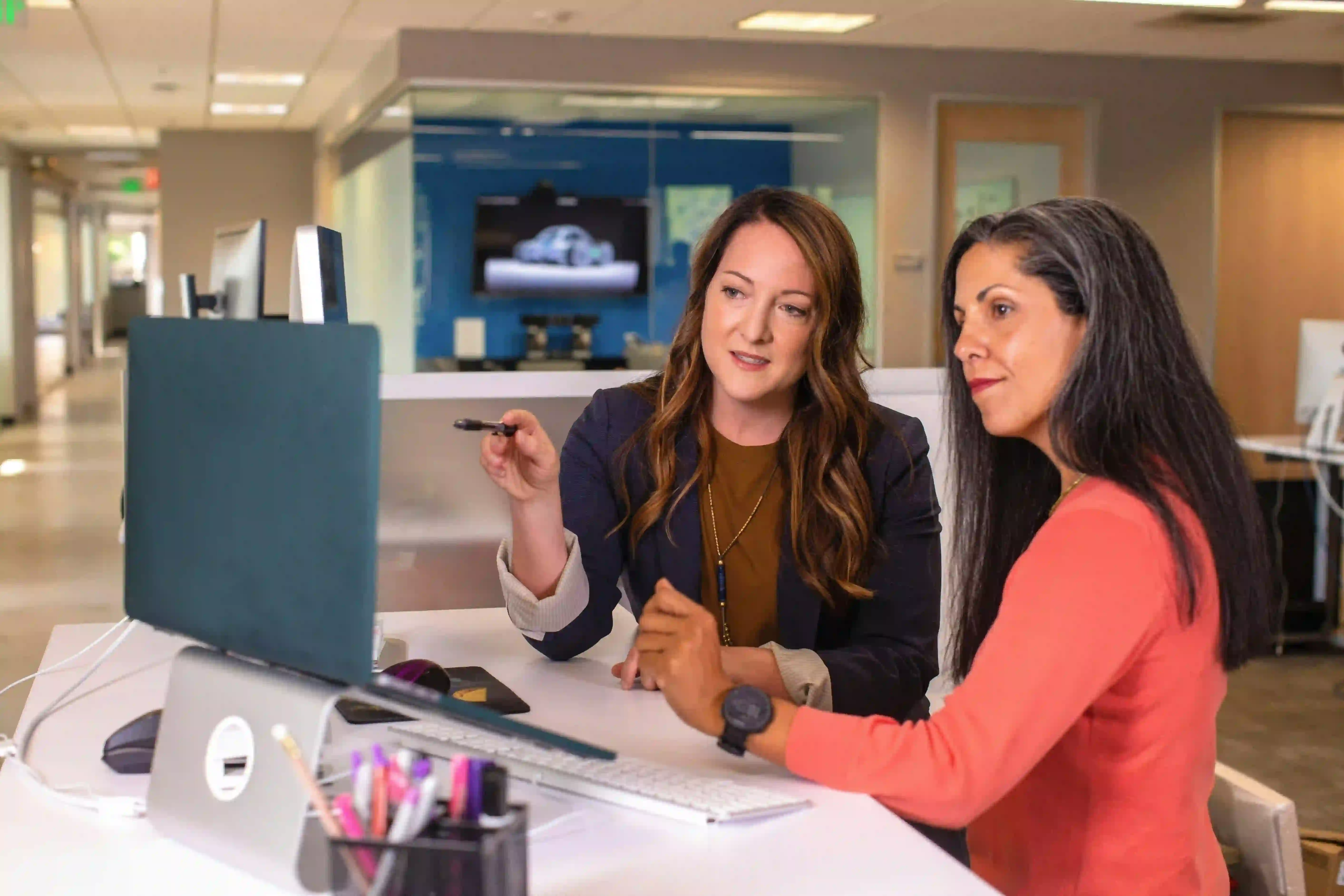 Two professional women collaborating in modern office representing open work permit workplace flexibility