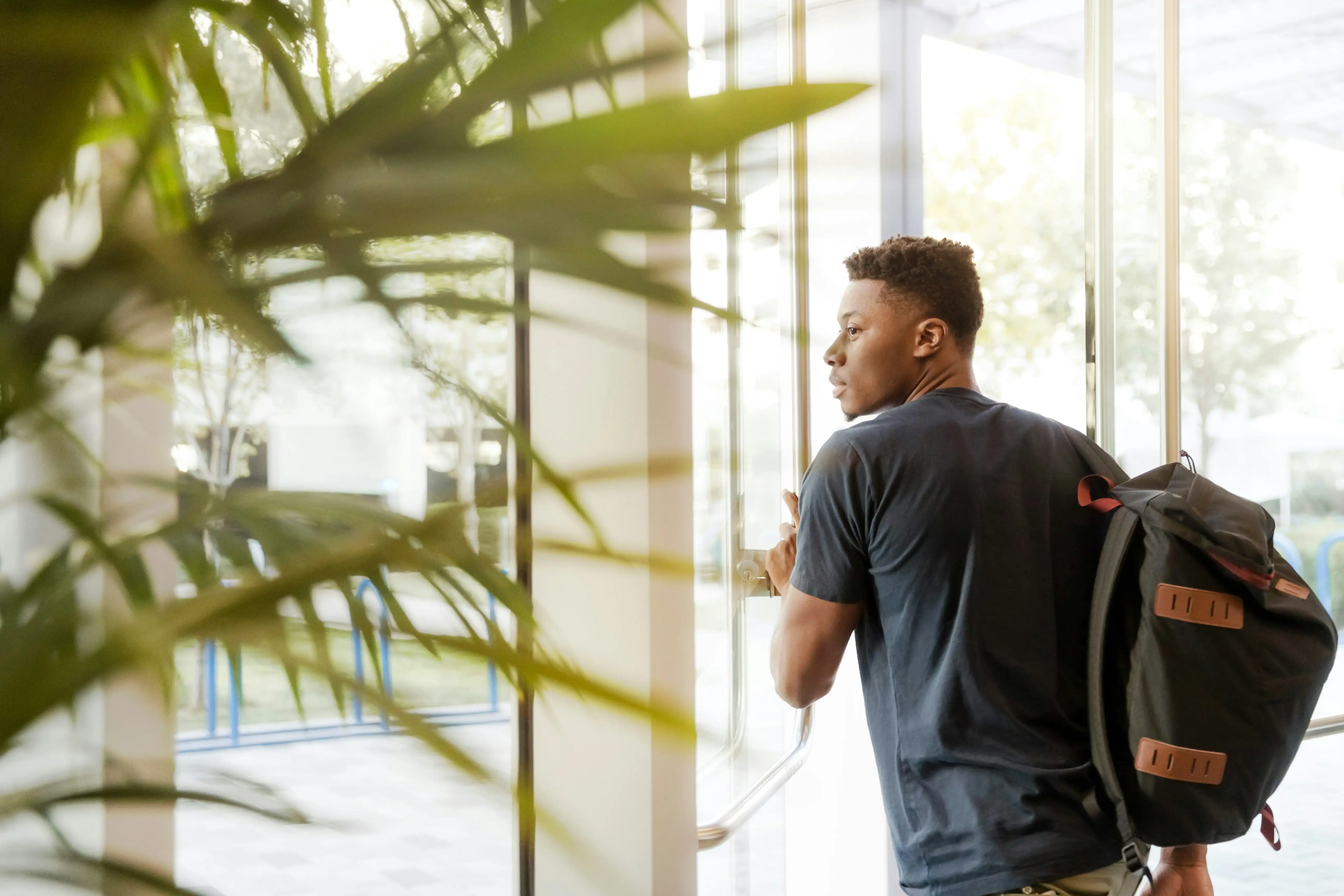 Student looking ahead through modern campus windows representing fast-track processing and educational aspirations