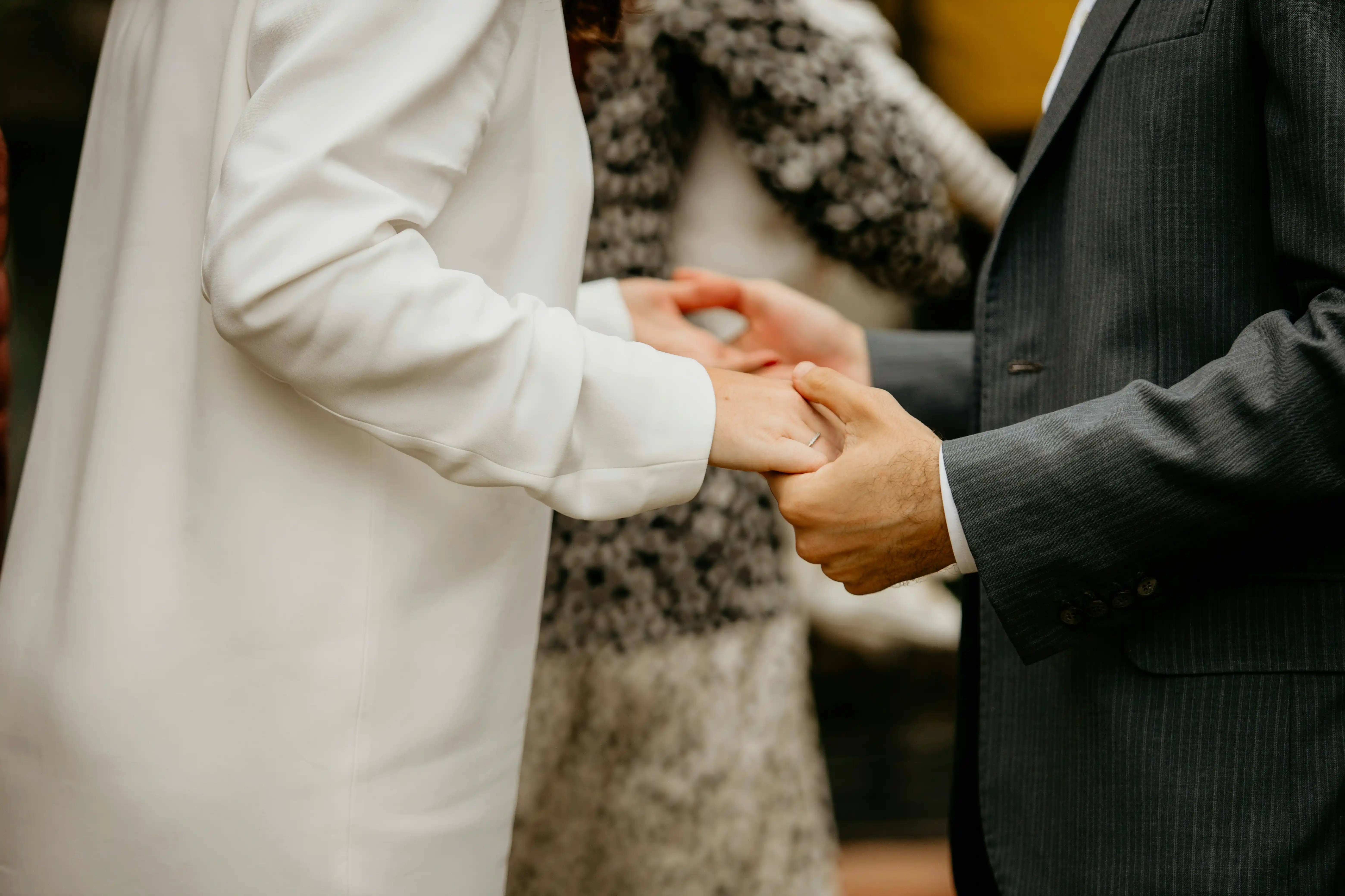 Couple holding hands during wedding ceremony, representing love and commitment in spousal sponsorship