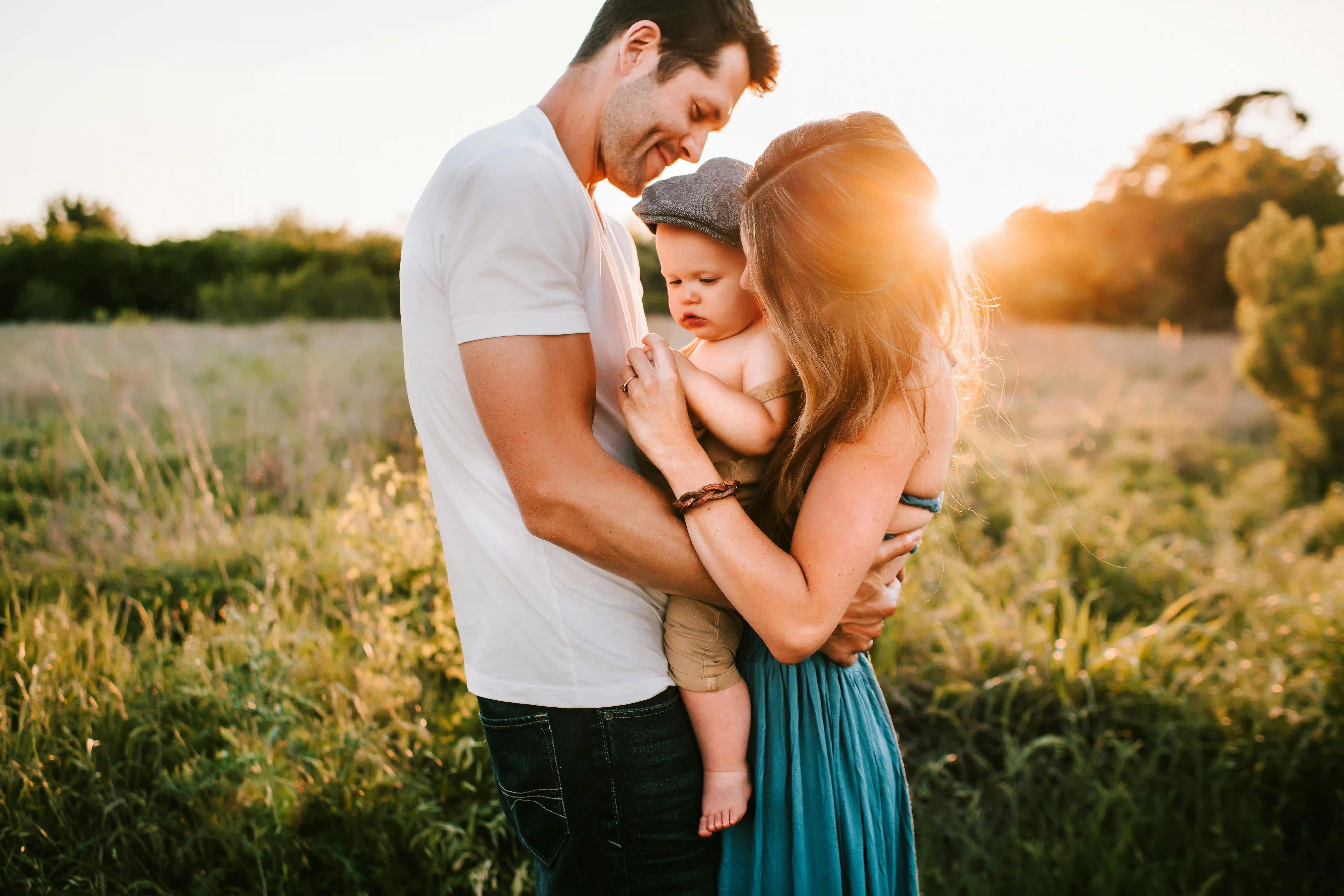 Happy family with parents and baby in golden hour outdoor setting representing building futures together