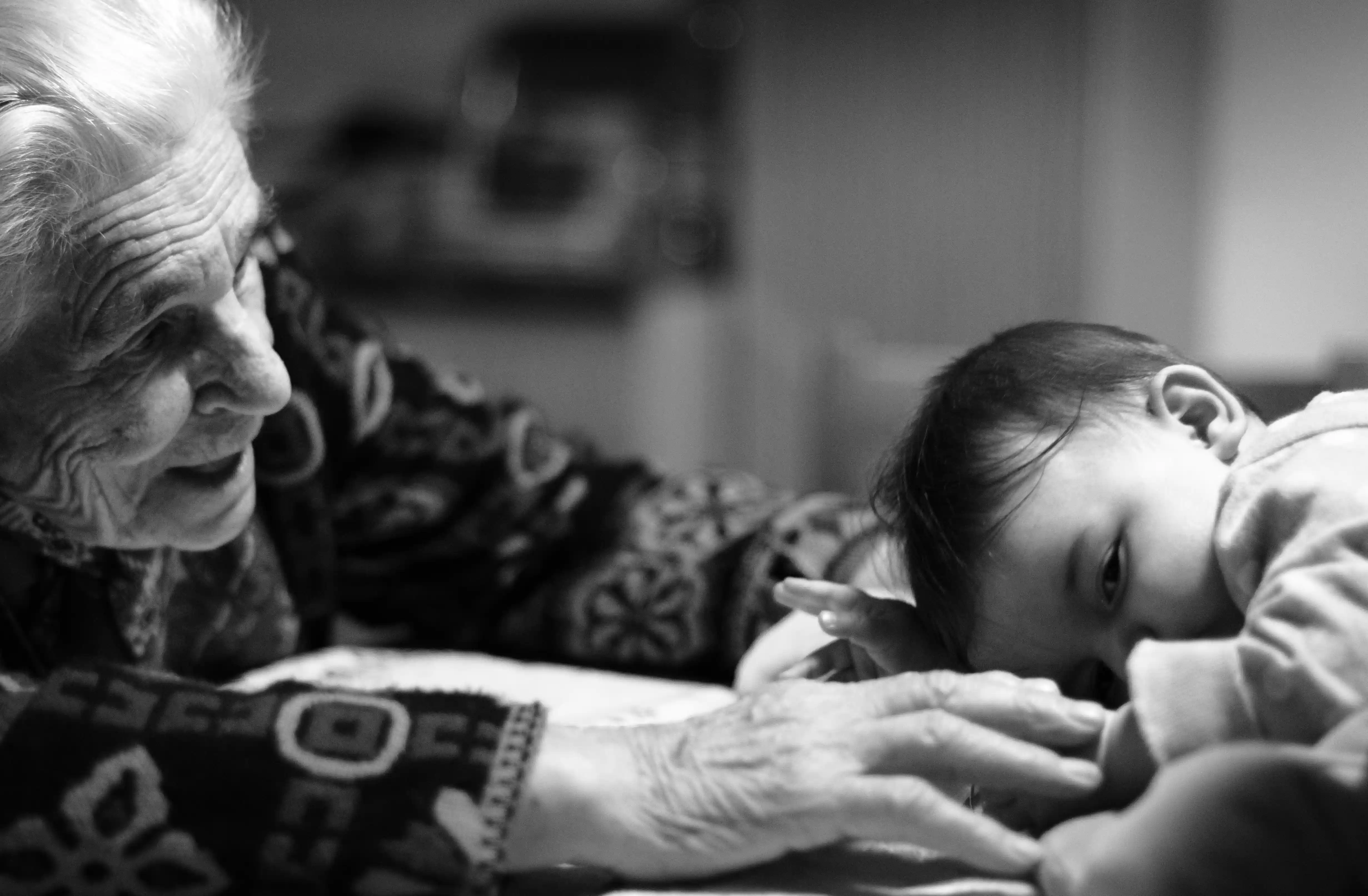 Elderly grandmother tenderly interacting with young grandchild representing bringing families together